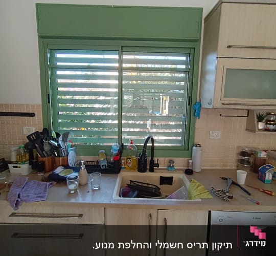מטבח עם חלון תריס ירוק וכלים בכיור